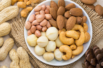 mixed nut, peanut almond macadamia and cashew nut on white plate, selective focus