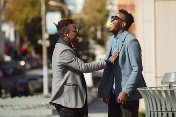 Two young african businessmen friends talking on the street