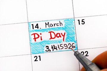 Woman fingers with pen writing reminder Pi Day in calendar.