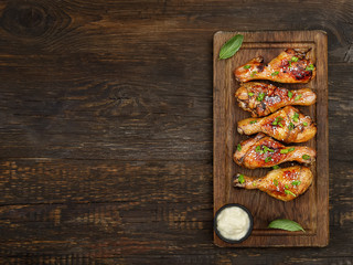 Roasted chicken drumsticks with sesame on a cutting board on a wooden background