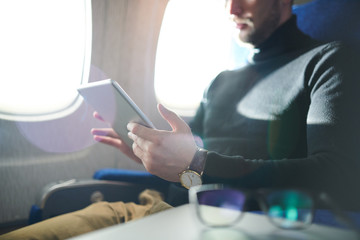 Mid section portrait of unrecognizable man using digital tablet while enjoying long first clas flight in plane, copy space - Powered by Adobe