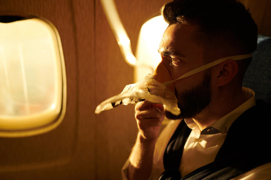 Side view portrait of handsome young man wearing oxygen mask in plane, copy pace
