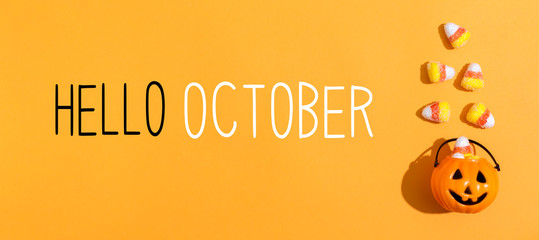 Hello October message with pumpkin overhead view on a solid color