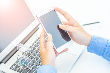 Man's hands holding a credit card and using laptop for online shopping.