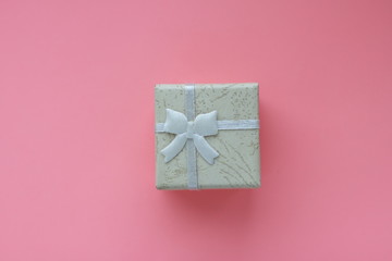 small present box with ribbon on pink background 