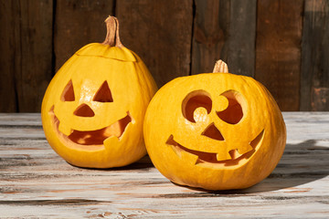 Funny carved Halloween pumpkins. Jack-o-lantern pumpkins with funny face expression on wooden background. Halloween symbols and traditions.