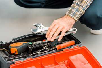 cropped image of plumber taking adjustable wrench from toolbox in kitchen