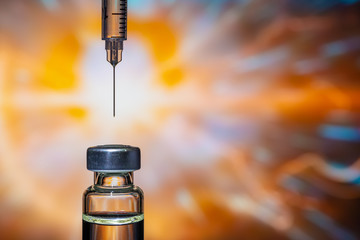 A syringe with the needle point to the vaccine vial on the colorful abstract background - obrazy, fototapety, plakaty