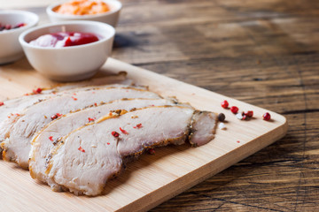 Pieces of smoked boiled pork on a wooden rustic Board with bread, sauces and spices on a wooden table