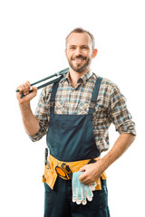 smiling plumber with tool belt holding monkey wrench and looking at camera isolated on white