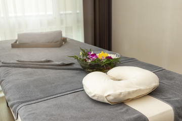 Pillow with Towel and flower on massage table in modern spa salon