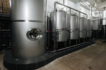 Modern brewery and equipment machinery tools for alcohol production. Steel vats or tanks and stainless pipes.