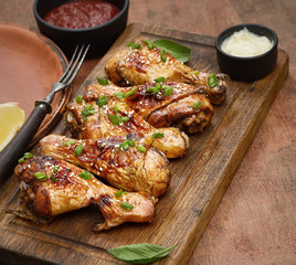 Roasted chicken drumsticks with sesame on a cutting board on a wooden background