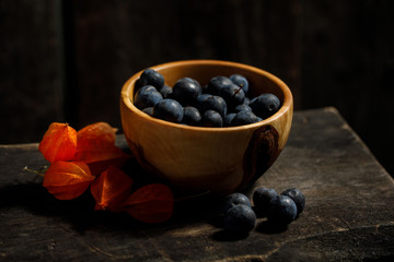 Rustic still life with fresh plum and phyllis berries.