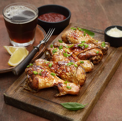 Roasted chicken drumsticks with sesame on a cutting board on a wooden background