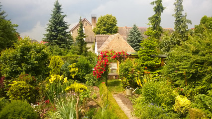 Abendstimmung in Bauerngarten mit Rosenbogen, immergrüner Garten mit Lebensbäumen, Grün im Frühling, Frühjahr und Sommerzeit 