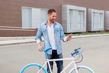 Casual guy next to a vintage bicycle with the mobile