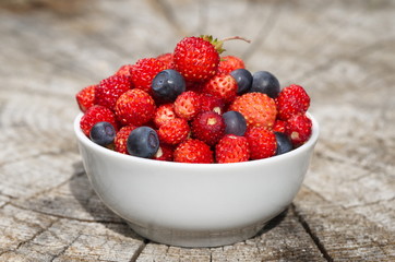 Fresh strawberries and blueberries on a wooden stump