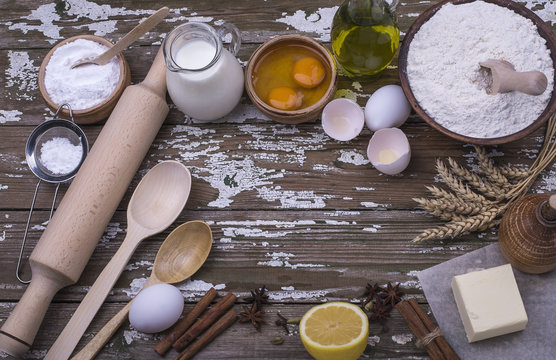 The set of natural products for preparation homemade cookies - flour, butter, sugar, spices, lemon, milk on a wooden table.
