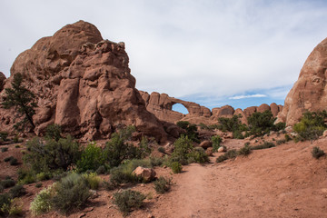 Fototapeta premium Tourists climb around in an arch inside of Arches National Park in Utah