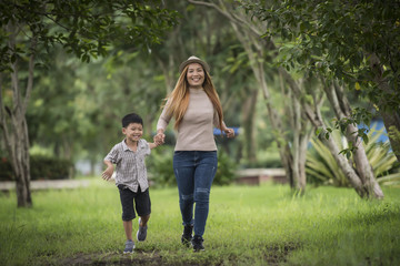Fototapeta premium Portrait of mother and son happy walking together in the park holding hand. Family concept.