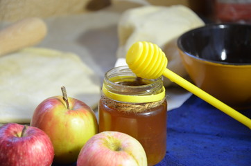 Various ingredients for winter seasonal baking and other recipes, honey, apples, herbs and spices on a dark blue background. Top view.