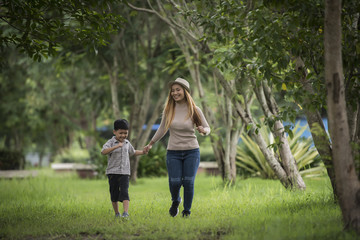Obraz premium Portrait of mother and son happy walking together in the park holding hand. Family concept.