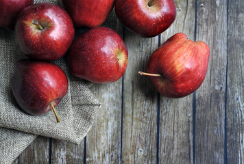 A group of fresh red apple on the wooden table with vintage sack
