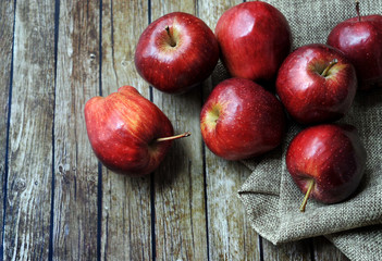 A group of fresh red apple on the wooden table with vintage sack