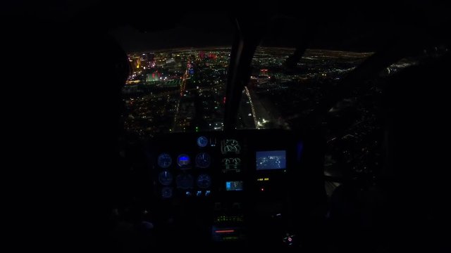 Helicopter interior on Las Vegas buildings and skyscrapers of downtown with illuminated casino hotels at night. Scenic flight above Vegas skyline by night in the Nevada United States of America.