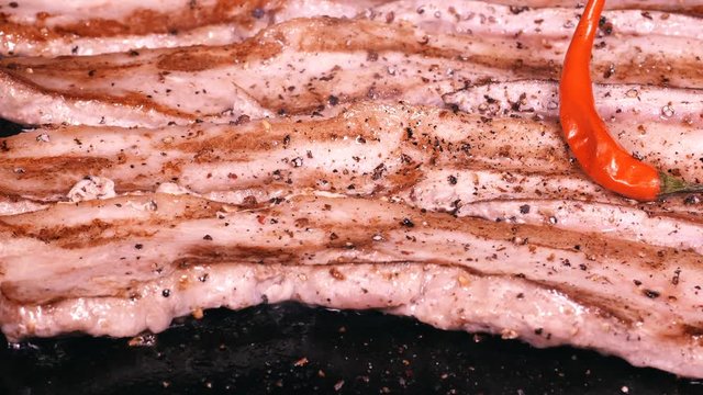UHD slow dolly shot of delicious pork bellies frying on the iron