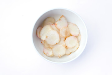 Slice galangal in a white bowl top view isolated on white background.