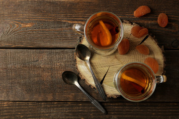 Autumn composition with hot tea and dried apricots on a brown wooden table with a place for inscription. top view