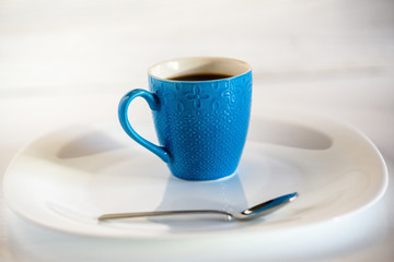 coffee in a blue cup on a light wooden background