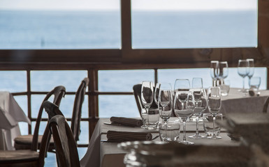 image of a group of glass glasses on the tables of a restaurant with the sea in the background