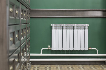 white aluminum radiator in the room on a green wall background