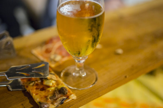 image with detail of a slice of pizza with a glass of beer