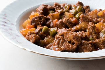 Turkish traditional tas kebab with potato, pea and tomato in a white plate