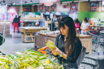 woman choosing corn in grocery shop