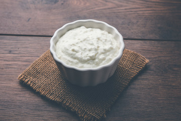 Plain curd or yogurt or Dahi in Hindi, served in a bowl over moody background. Selective focus