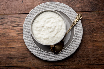 Plain curd or yogurt or Dahi in Hindi, served in a bowl over moody background. Selective focus