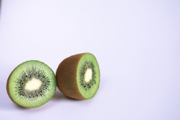 A kiwi fruit is sliced on a white background