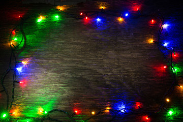 multicolored Christmas lights on a wooden background