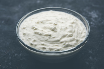 Plain curd or yogurt or Dahi in Hindi, served in a bowl over moody background. Selective focus