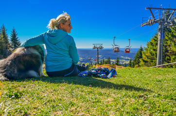 Frau sitzt in der Sonne an einer Seilbahn im Fichtelgebirge