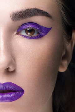 Close-up of a woman's beauty with fashionable make-up. Lilac color shooter and lipstick for lips in tone. Cosmetology, cosmetics. Long eyelashes and thick eyebrows, perfectly clean skin of the face