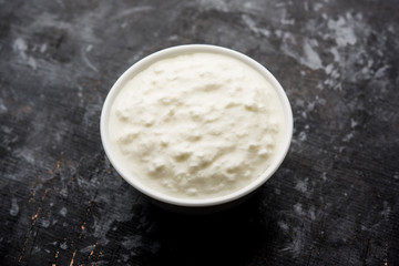 Plain curd or yogurt or Dahi in Hindi, served in a bowl over moody background. Selective focus