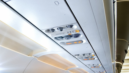 Closeup image of fasten seat belts sign and air vents above the passenger seat