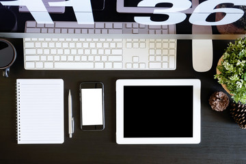 Office desk with tablet and smartphone mockup on black wooden table, A top view shot.