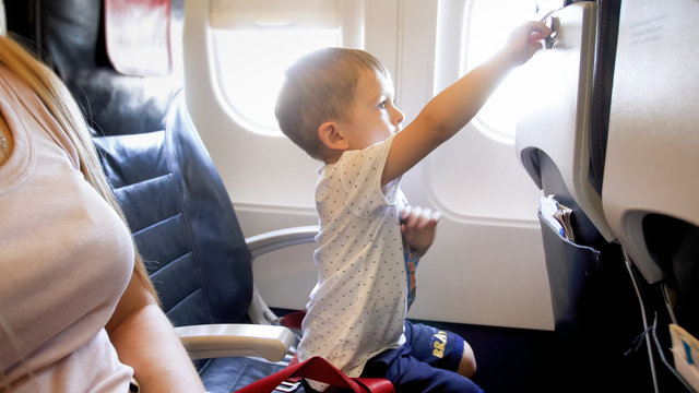 Portrait of little boy locking foldable table on seat at passenger aircraft